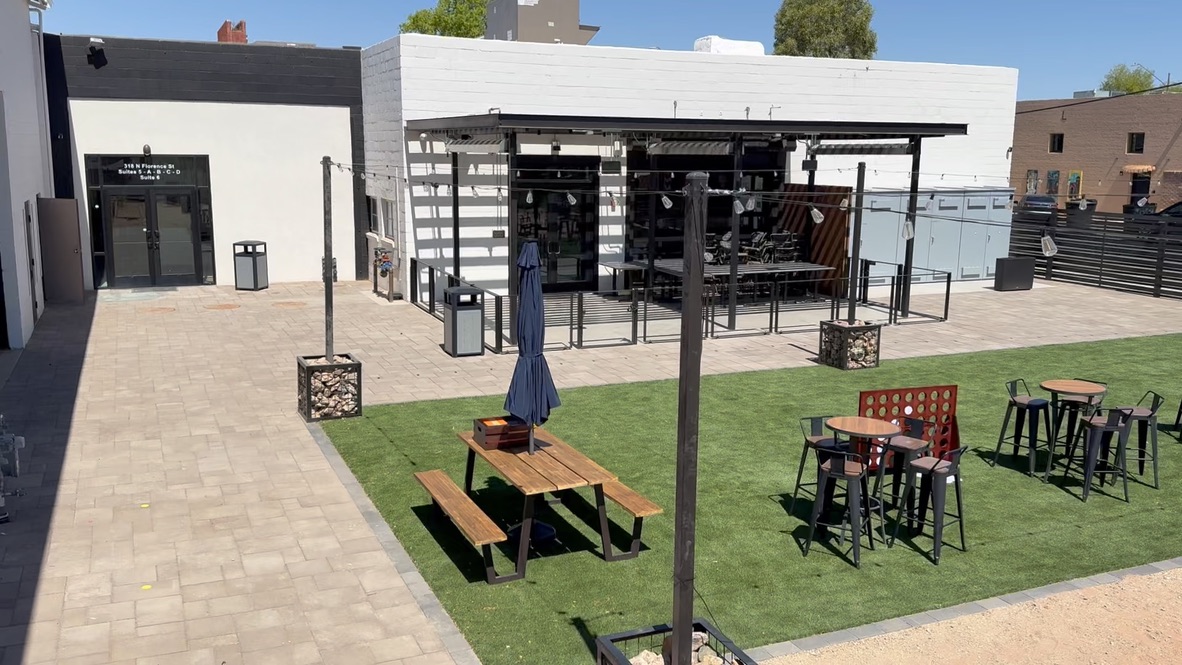 Terminal 318 patio with picnic tables, umbrella, and storefront entrance
